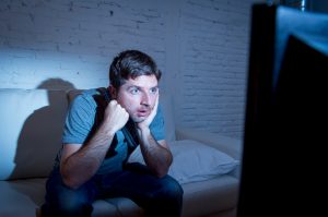 television addict man watching tv holding remote control mesmerized